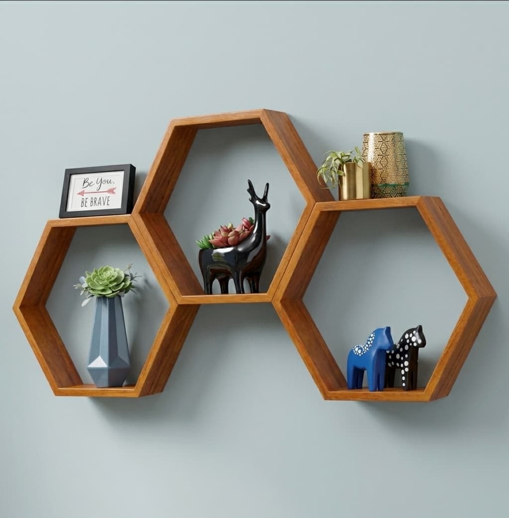 Set of three walnut hexagon wall shelves holding plants, frames and decor